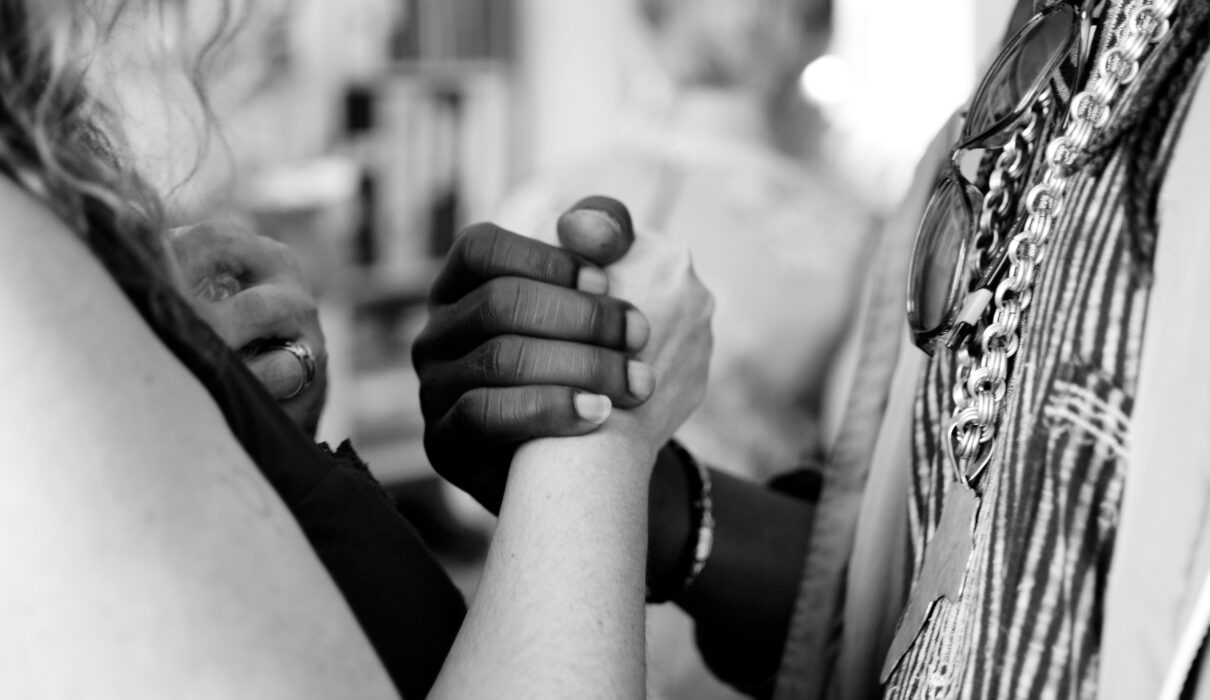 grayscale photo of man and woman holding their hands