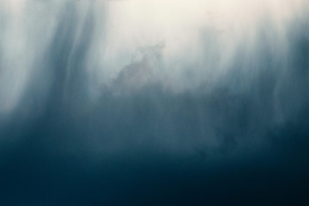 a bird flying through a cloudy blue sky