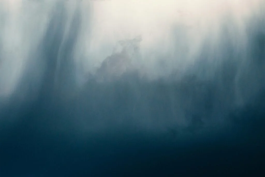 a bird flying through a cloudy blue sky