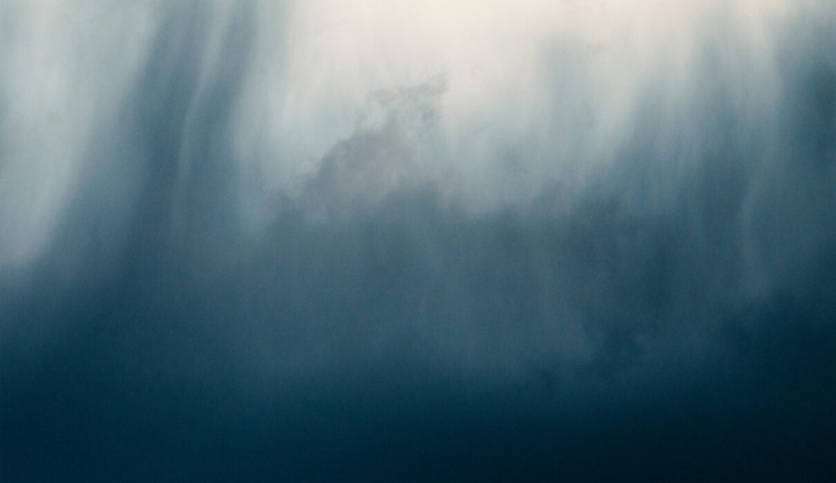 a bird flying through a cloudy blue sky