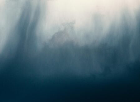 a bird flying through a cloudy blue sky