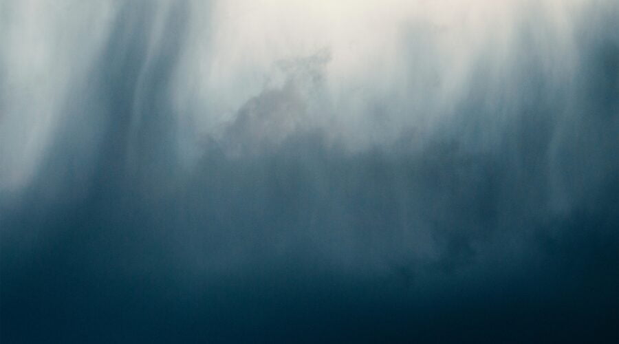 a bird flying through a cloudy blue sky