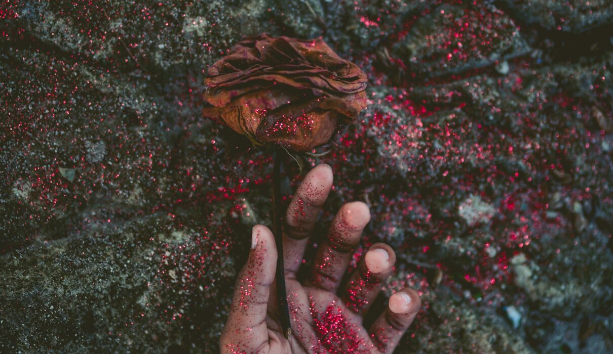 person's left hand covered with red glitters