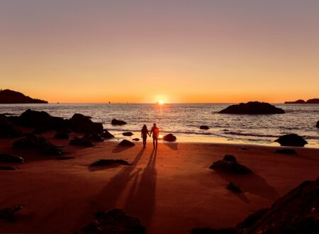 man in black shorts walking on beach during sunset