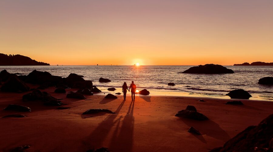 man in black shorts walking on beach during sunset