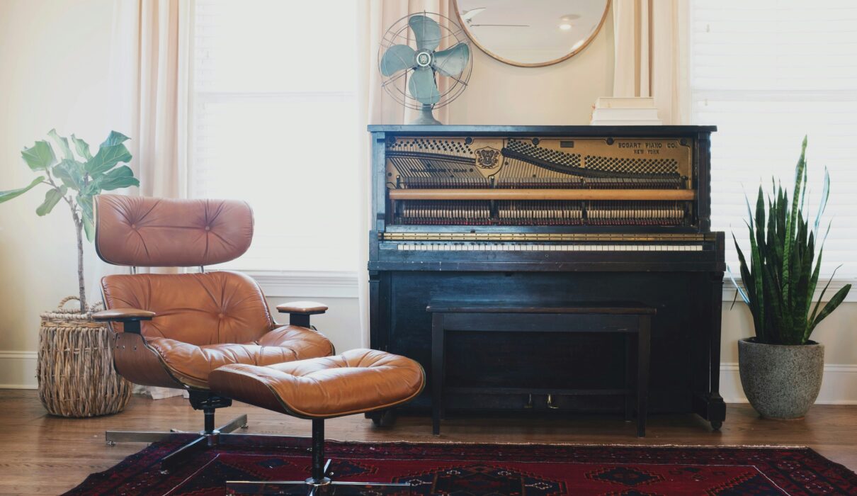 black upright piano near brown leather padded chair