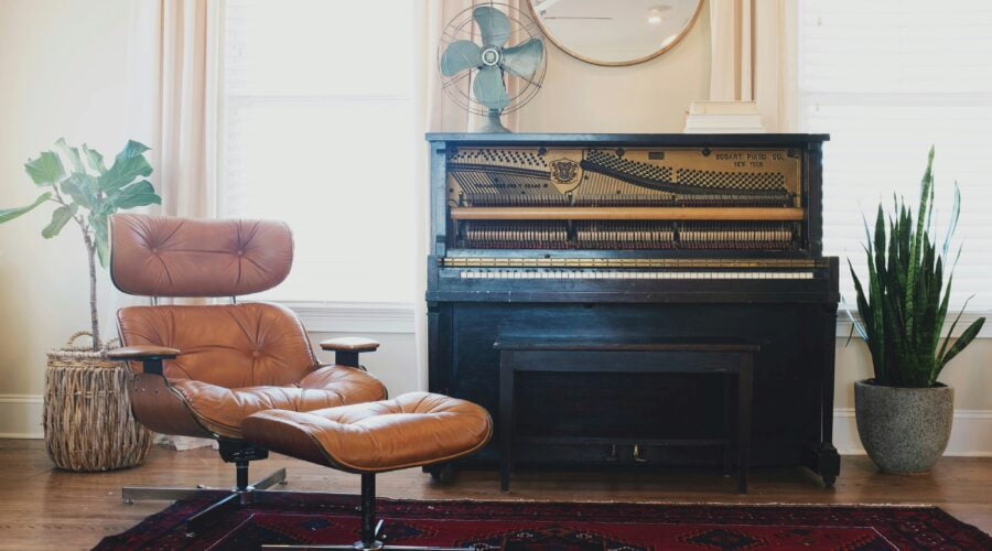 black upright piano near brown leather padded chair