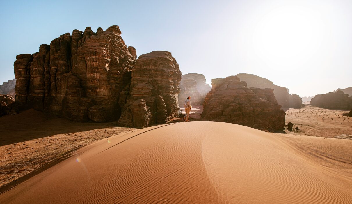 a person standing on top of a sand dune