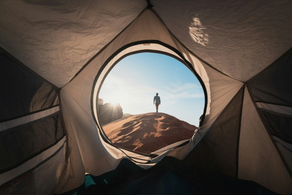 a man standing in a tent looking out into the distance