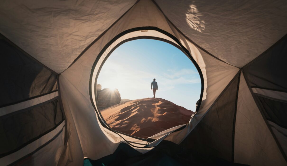 a man standing in a tent looking out into the distance