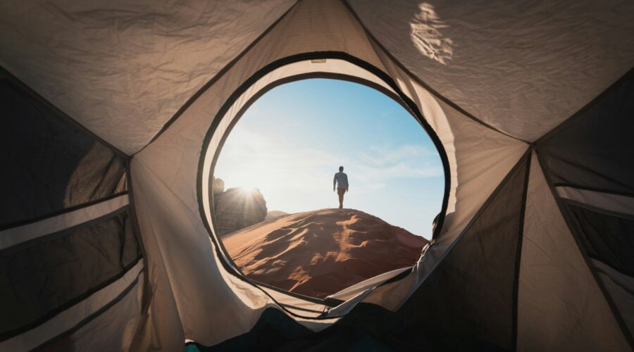 a man standing in a tent looking out into the distance