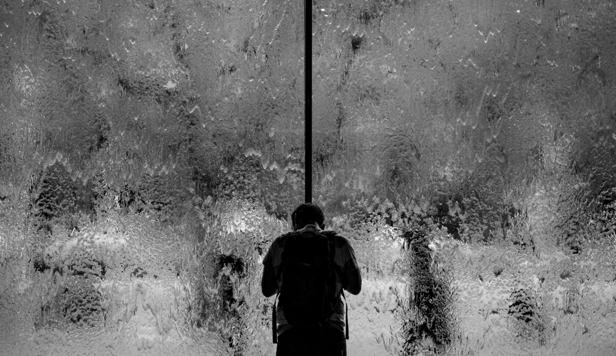 man standing on glass wall with pouring water