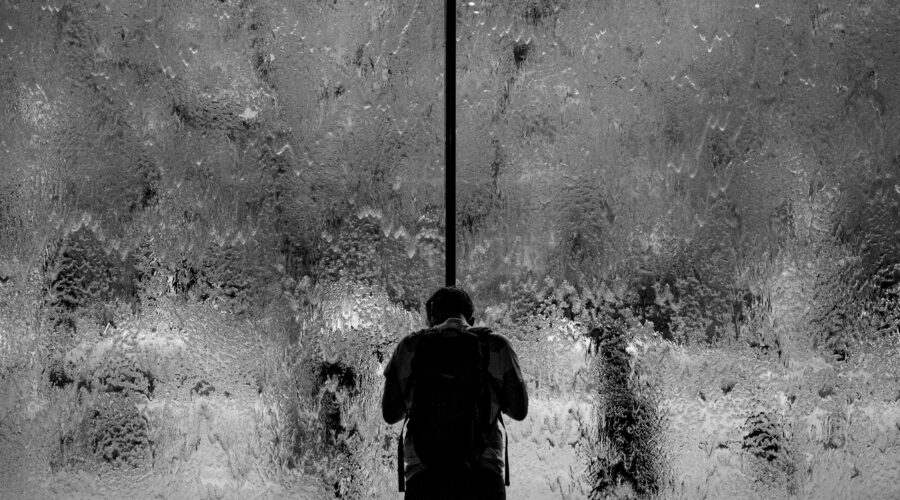 man standing on glass wall with pouring water