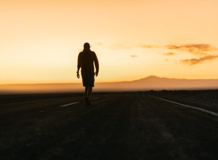 a man walking down a road at sunset